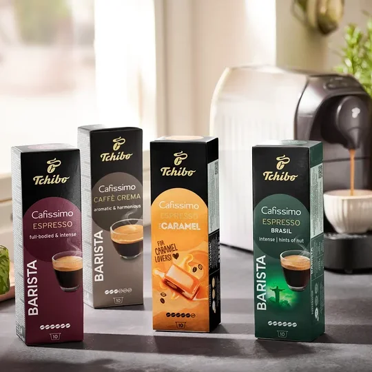 Fünf Packungen Cafissimo BARISTA Espresso Brasil Kapseln und eine Kaffeemaschine. Kaffee fließt aus der Kaffeemaschine in eine Tasse.