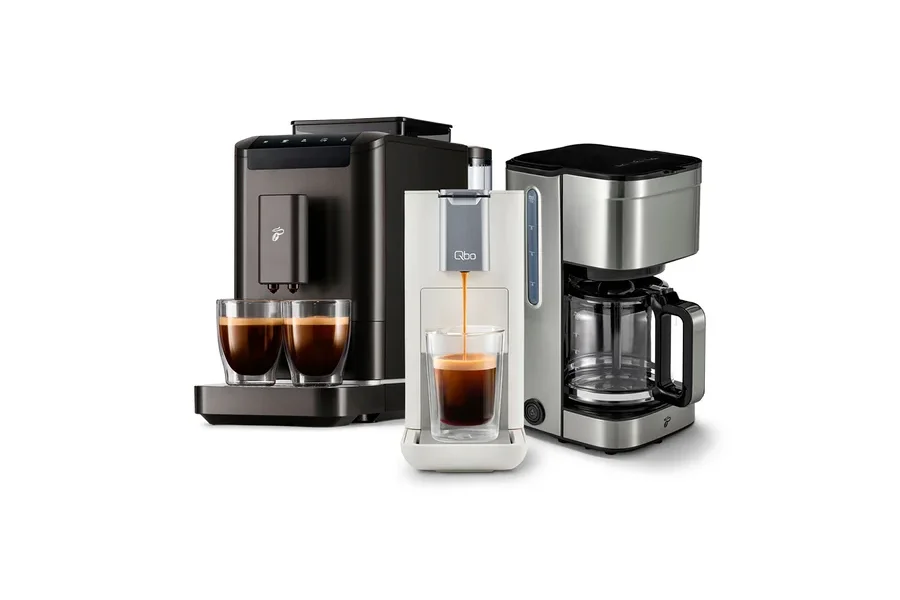 Drei Kaffeemaschinen stehen nebeneinander, aus der mittleren läuft Kaffee in ein Glas.