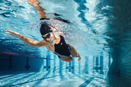Frau schwimmt im Schwimmbad unter Wasser und trägt einen schwarzen arena Feel Damen Badeanzug Lily Swim Pro Back Bustier.