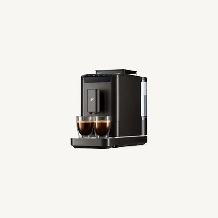 Dunkelgraue Kaffeemaschine, die zwei gefüllte Kaffeetassen auf einem Abtropfgitter zubereitet.