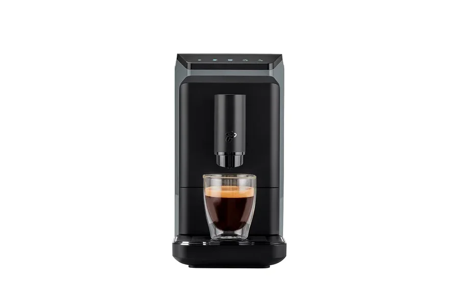 Eine schwarze Kaffeemaschine mit einem Glas Espresso darunter.