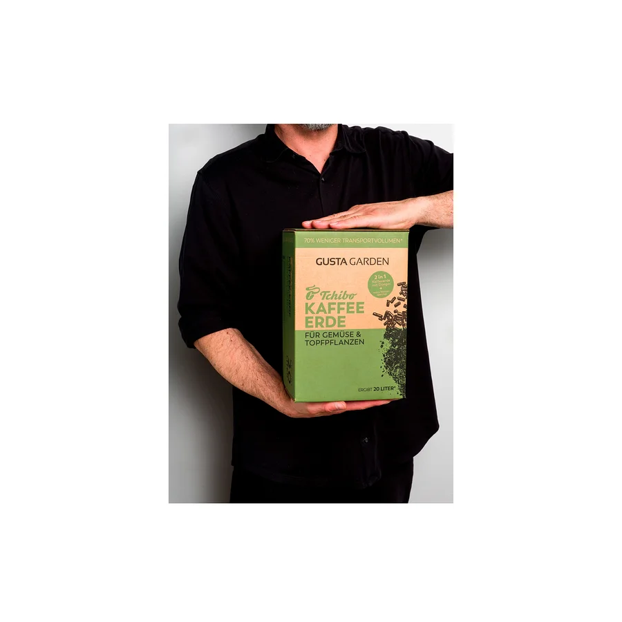 Eine Person hält eine Packung Tchibo Kaffee Erde für Gemüse und Topfpflanzen der Marke Gusta Garden.