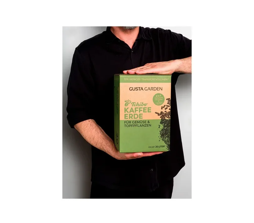 Eine Person hält eine Packung Tchibo Kaffee Erde für Gemüse und Topfpflanzen der Marke Gusta Garden.