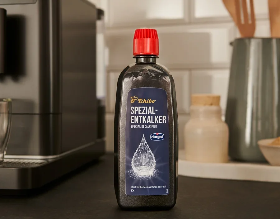Eine schwarze Flasche durgol® Spezial-Entkalker, 400 ml, steht auf der Theke neben einer Kaffeemaschine.