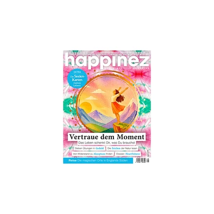happinez Magazincover: Frau steht mit ausgebreiteten Armen auf Felsen vor Sonnenuntergang über Bergen, umrahmt von goldenem Kreis. Hintergrund: pink-grün-blaues Batikmuster. Titel: Vertraue dem Moment.