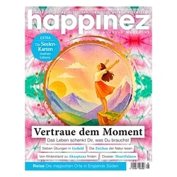 happinez Magazincover: Frau steht mit ausgebreiteten Armen auf Felsen vor Sonnenuntergang über Bergen, umrahmt von goldenem Kreis. Hintergrund: pink-grün-blaues Batikmuster. Titel: Vertraue dem Moment.