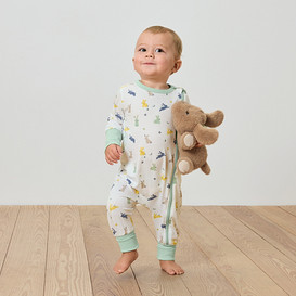 Ein Baby steht auf einem Holzboden und hält einen Plüsch-Elefanten.
