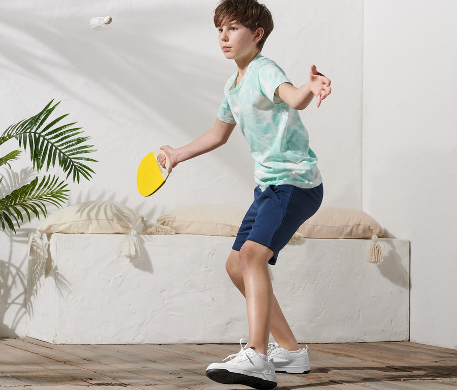 Junge schlägt Federball mit gelbem Schläger aus Padminton-Set.