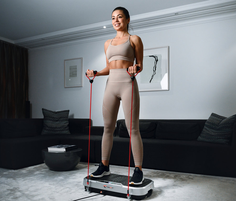 Frau trainiert mit Christopeit Vibrationstrainer Vibro VBT 4200 und roten Widerstandsbändern.