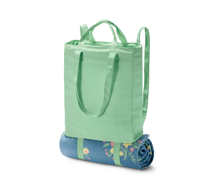 Eine grüne 2-in-1-Kühl-Rucksacktasche mit einer zusammengerollten blauen Decke mit Blumenmuster.