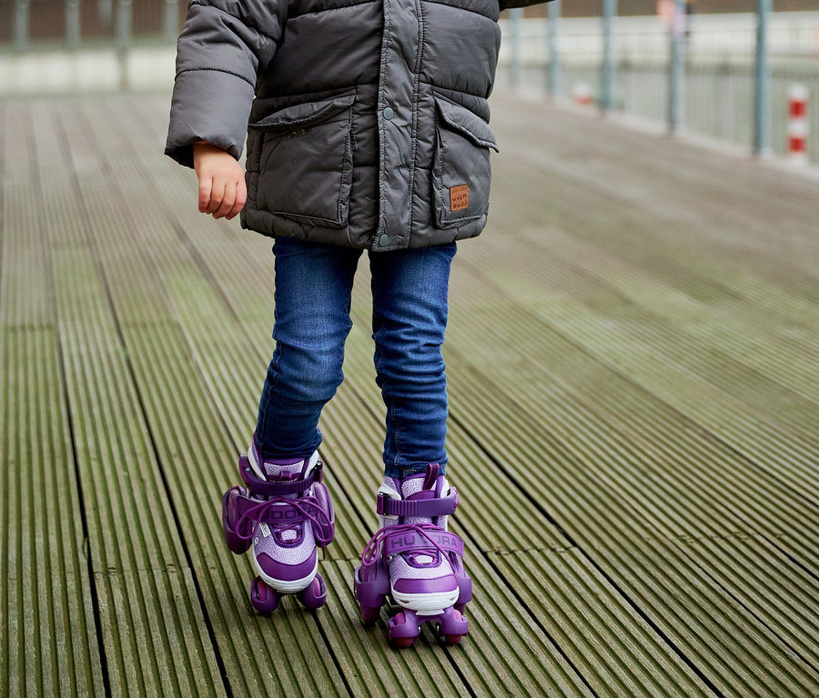 Kind auf HUDORA Rollschuhen »My First Quad«, Gr. 26–29, lavender, wird von einer erwachsenen Person an der Hand gehalten.