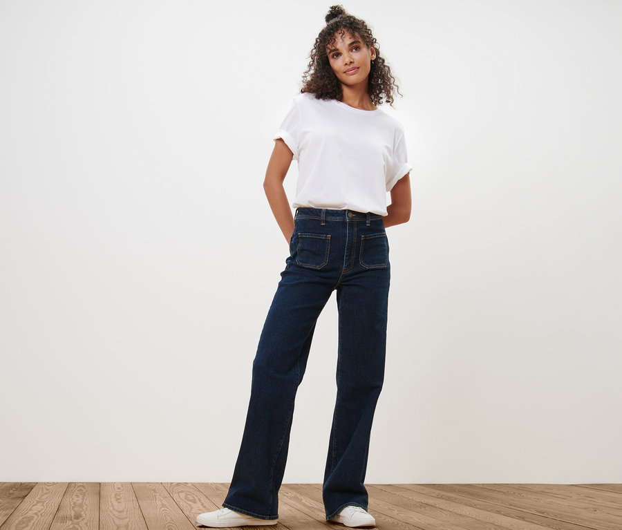 Frau posiert in Flared Jeans – Fit »Cara« und weißem T-Shirt.