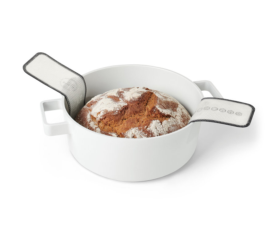 Ein gebackenes Brot in einem weißen Topf mit einer Dauerbackmatte.