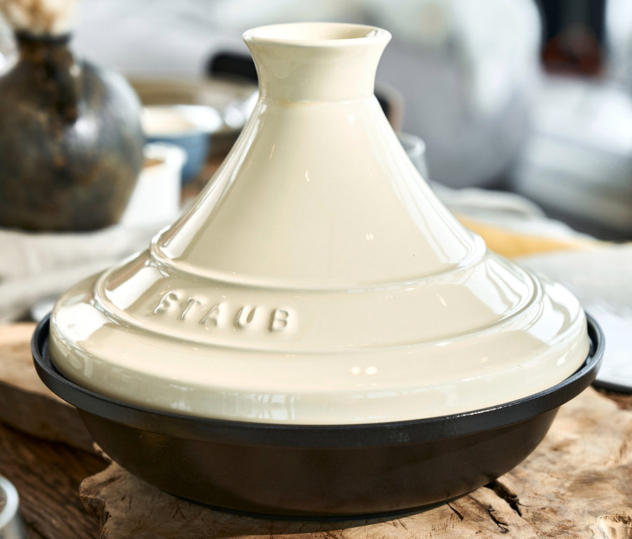 Nahaufnahme einer STAUB Gusseisen-Tajine, creme, 28 cm auf einem Holztisch.