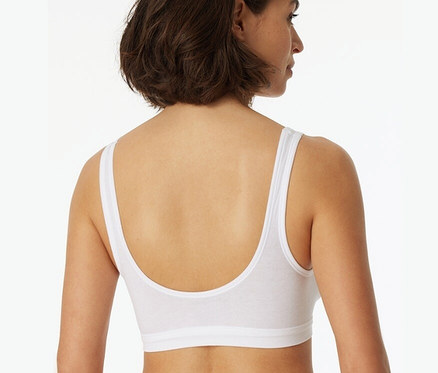 Rückansicht einer Frau mit braunen Haaren, die ein weißes 2 SCHIESSER Bustiers mit Cups und Bio-Baumwolle trägt.