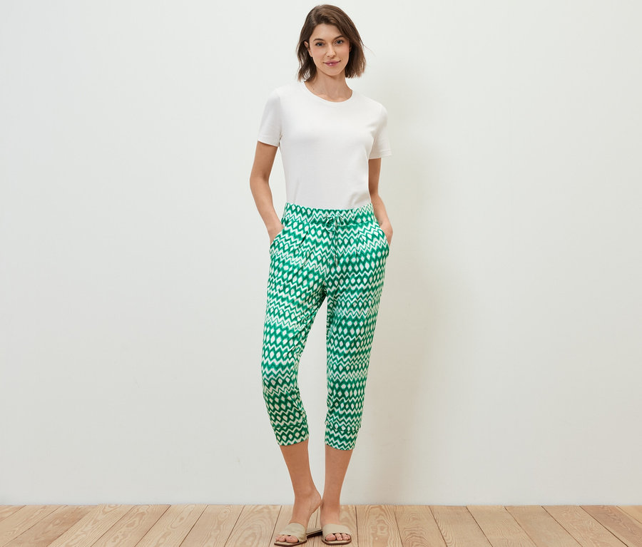 Frau steht mit Händen in den Taschen in einer bedruckten 3/4-Jerseyhose.