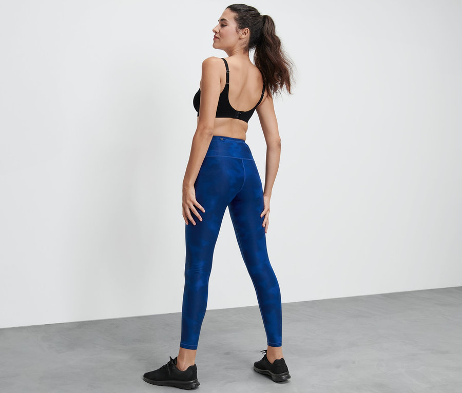 Frau steht mit dem Rücken zur Kamera und trägt eine Sporttight.