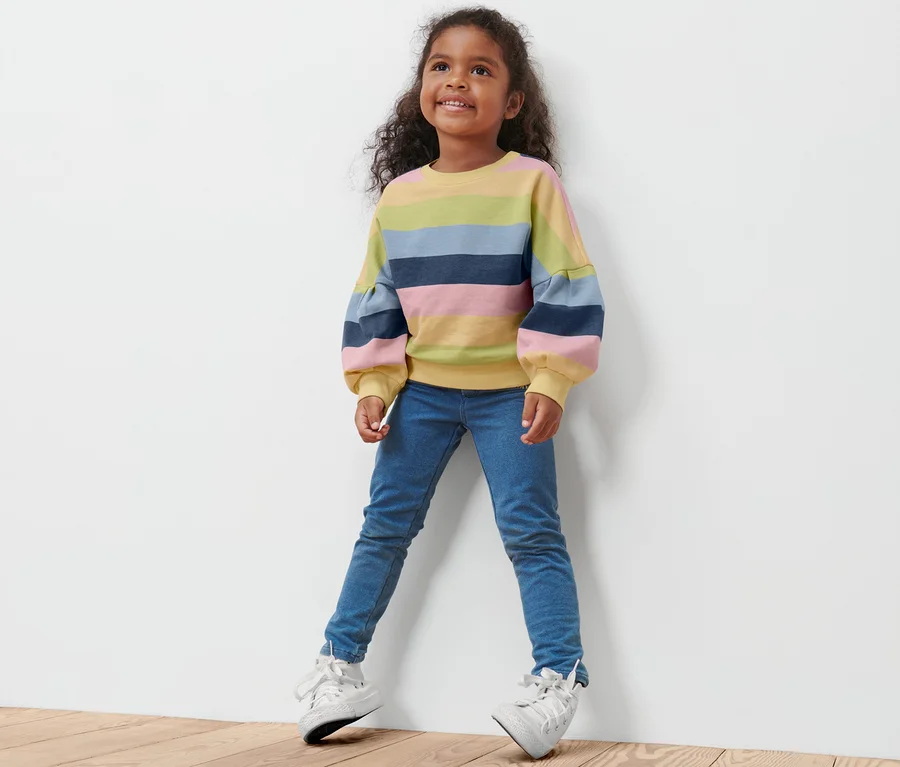 Mädchen trägt ein Kleinkind-Sweatshirt mit bunten Streifen.