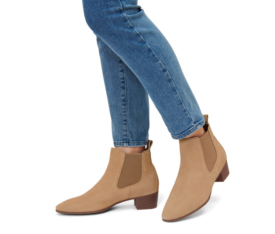 Beine in blauen Jeans und Stiefeletten aus Veloursleder.