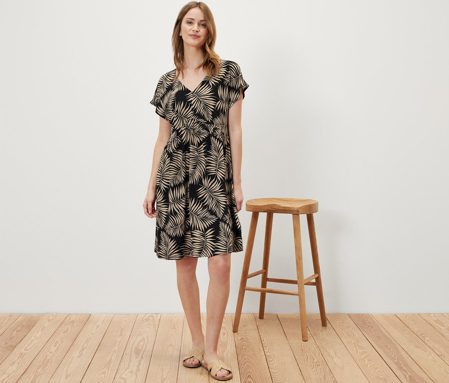 Frau steht und trägt ein bedrucktes Jerseykleid.