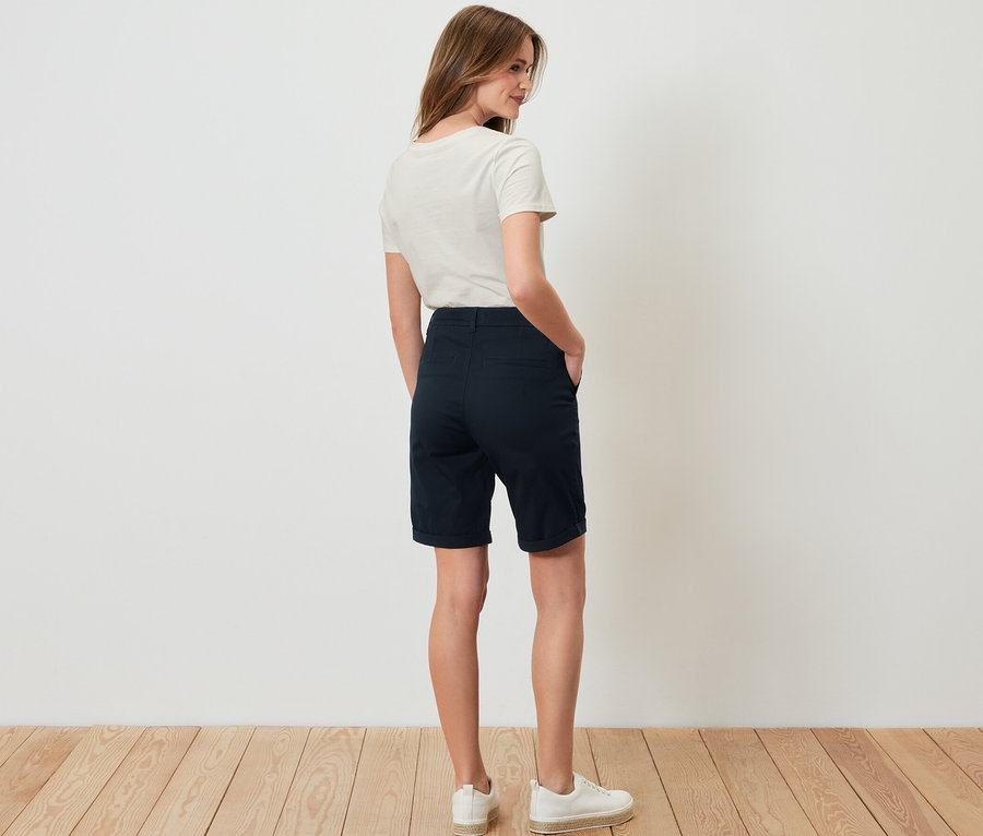 Frau steht mit dem Rücken zur Kamera und trägt marineblaue Chino-Shorts.