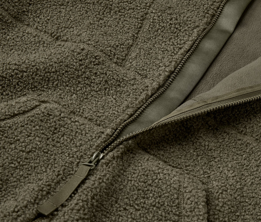 Detailaufnahme einer olivgrünen, flauschigen Jacke mit Reißverschluss.