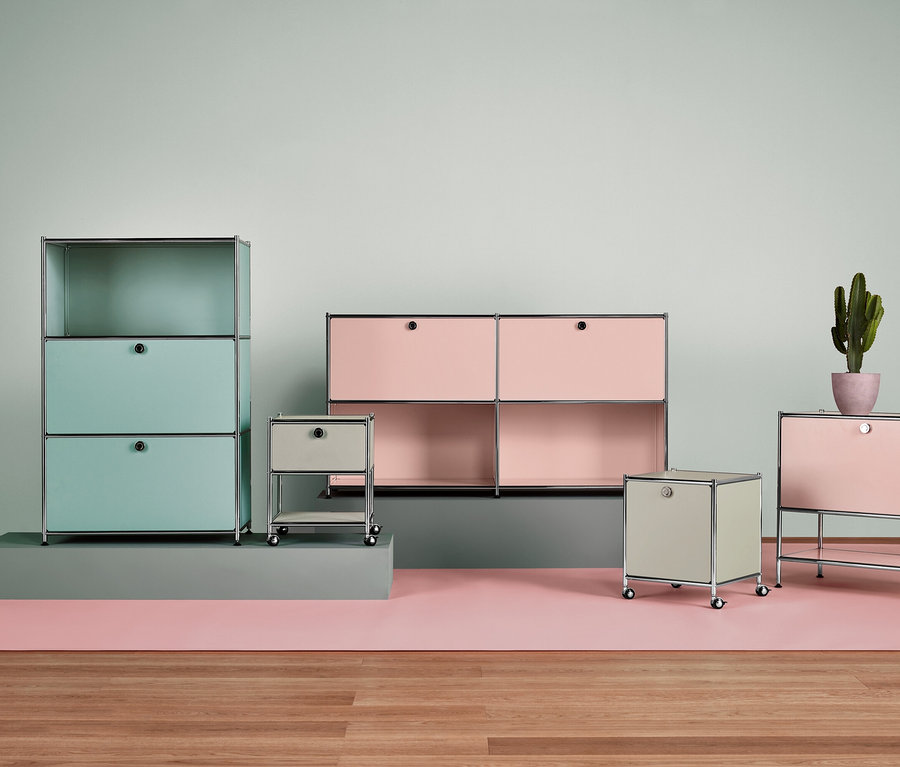 Verschiedene USM Haller Möbelstücke in Pastellfarben mit einem Kaktus in einem Blumentopf.