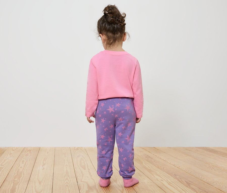 Mädchen mit dem Rücken zur Kamera trägt ein rosa Sweatshirt und eine lila Hose mit Sternen.