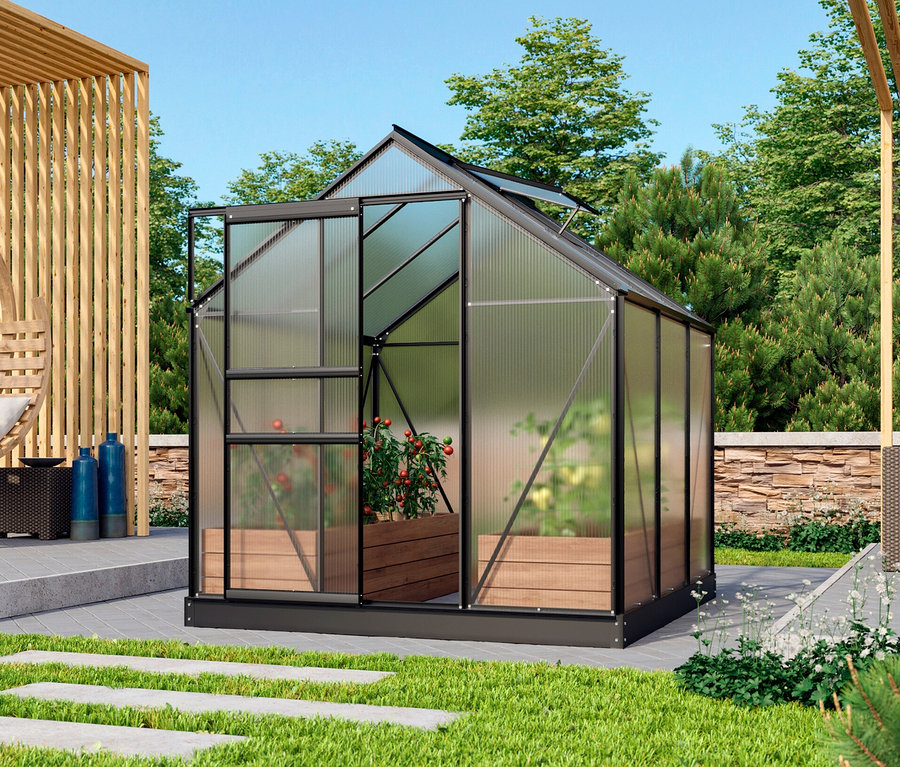 Im Garten steht ein Vitavia Einsteiger-Gewächshaus inkl. Fundamentrahmen. Im Inneren befinden sich Pflanzen in einem Holzkasten. Im Hintergrund sind eine Kreisschaukel und ein blauer Sessel zu sehen.