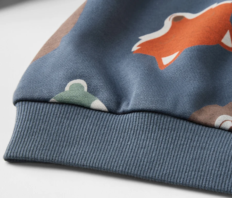 Detailansicht eines blauen Kinder-Sweatshirts mit Fuchsmuster.