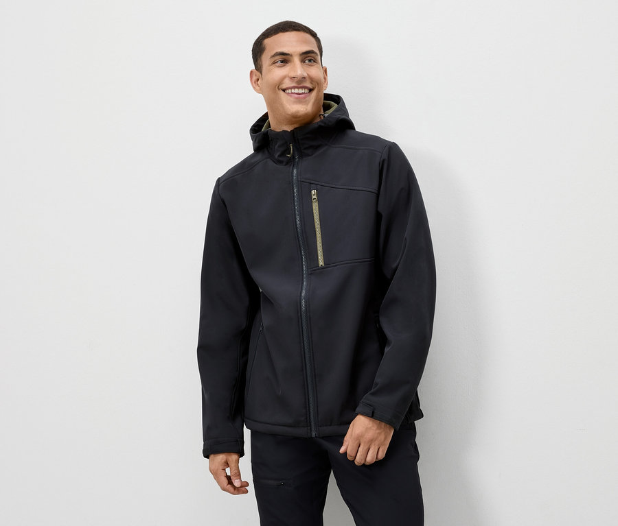 Mann lächelt und trägt eine schwarze Jacke mit Kapuze.