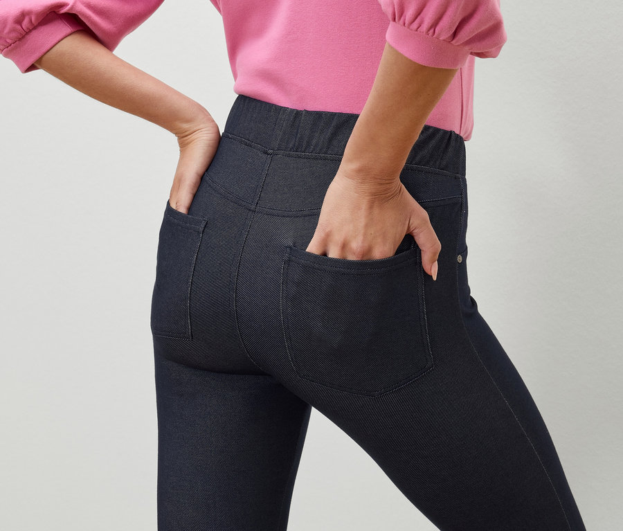 Frau hat Hand in Tasche von dunkelblauen Jeggings.