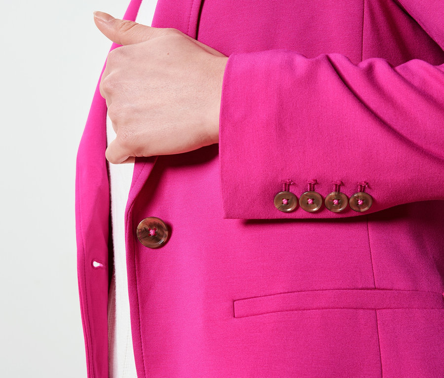 Nahaufnahme eines pinkfarbenen Blazers mit braunen Knöpfen an Ärmel und Verschluss.