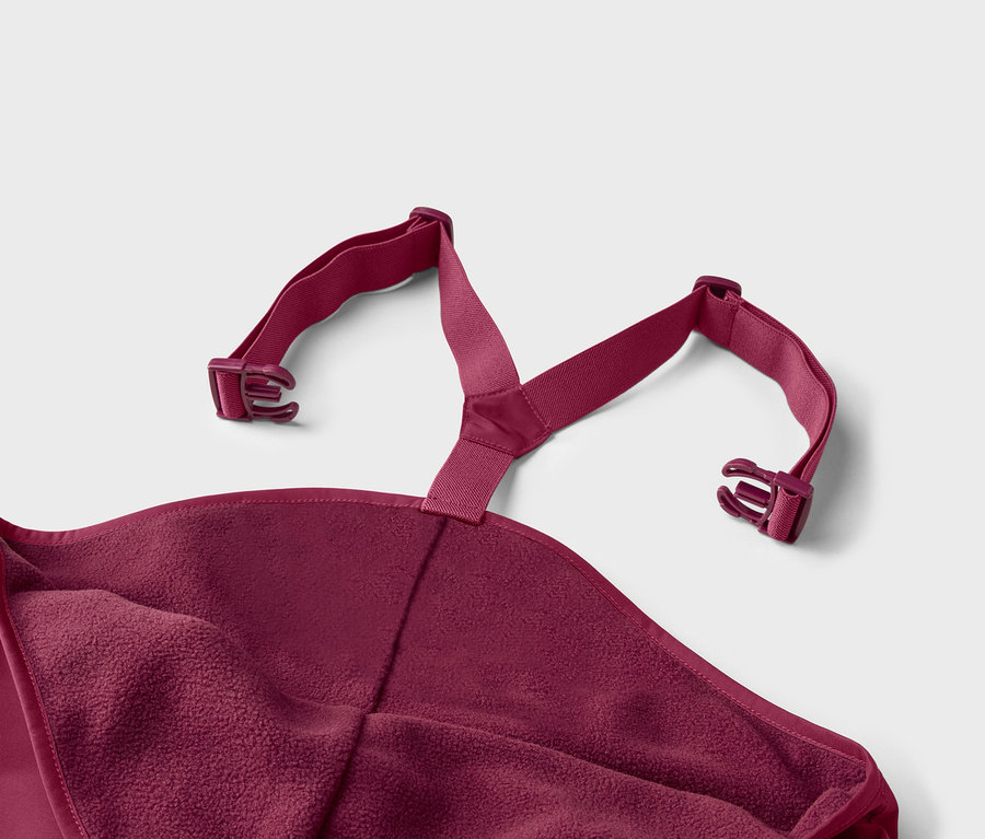 Nahaufnahme eines weinroten Badeponchos mit Fleece-Futter und verstellbaren Trägern mit Schnallen vor einem hellgrauen Hintergrund.
