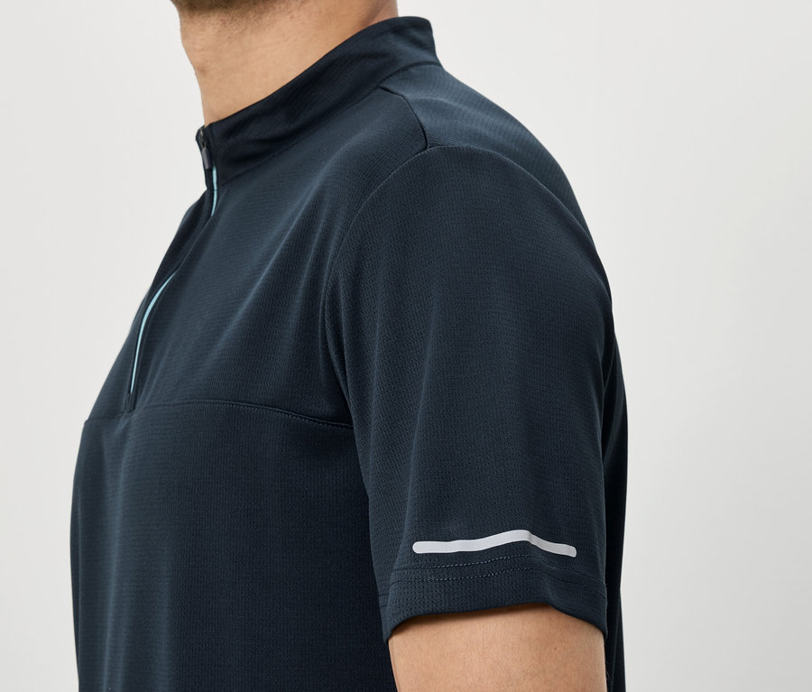 Mann trägt marineblaues Kurzarmhemd mit Reißverschluss und reflektierendem Streifen am Ärmel.