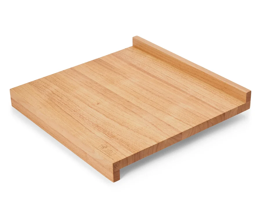 Ein rechteckiges, hellbraunes Schneidebrett aus Holz liegt diagonal auf einer weißen Oberfläche.