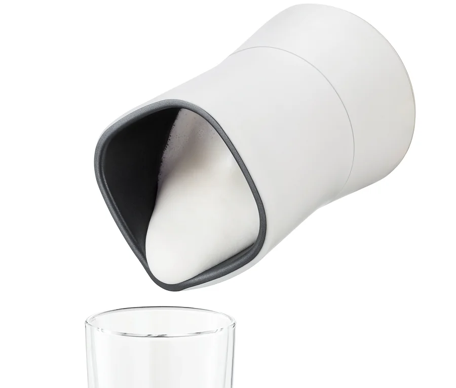 Weißer elektrischer Milchaufschäumer giesst Milchschaum in ein Glas.