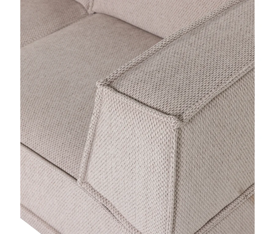 Nahaufnahme eines hellbeigen Sofas aus Webstoff, das die strukturierte Armlehne und einen Teil der getufteten Rückenlehne zeigt.