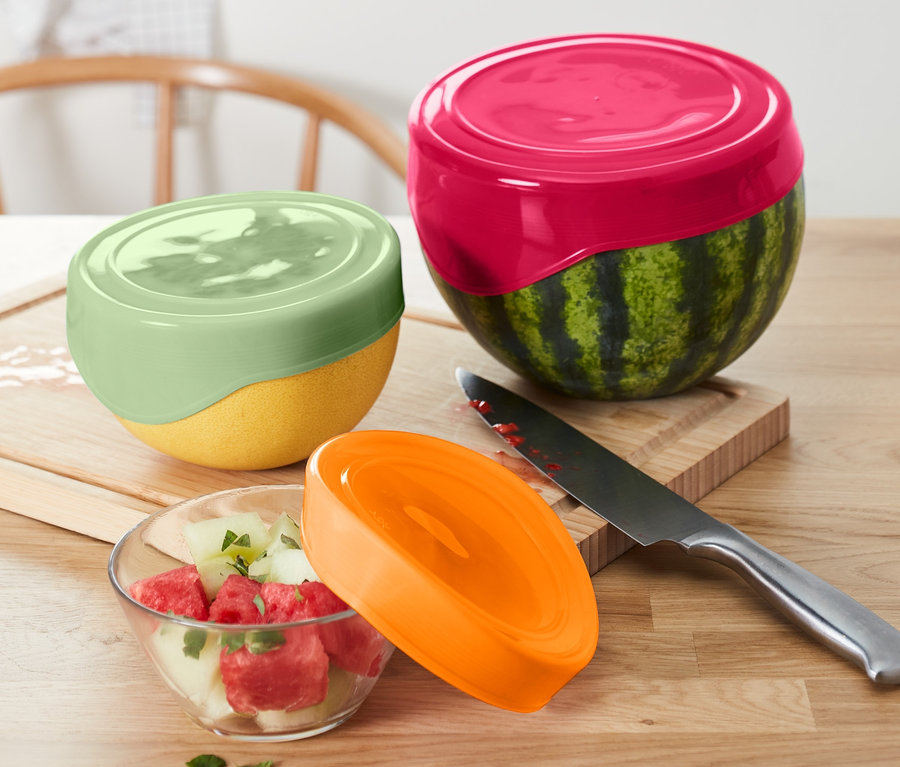 Eine halbe Wassermelone und eine halbe gelbe Melone sind mit 3 Silikon-Frischhaltedeckeln abgedeckt. Zu einem Wassermelonensalat gehören ein orangefarbener Deckel und ein Messer.