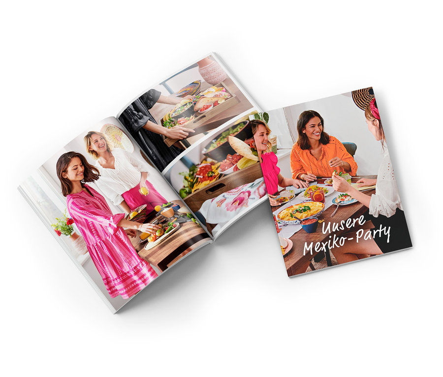 Geöffnete Broschüre mit Fotos von Menschen, die essen und Essen zubereiten. Holzteller und XL-Tablett sind sichtbar.