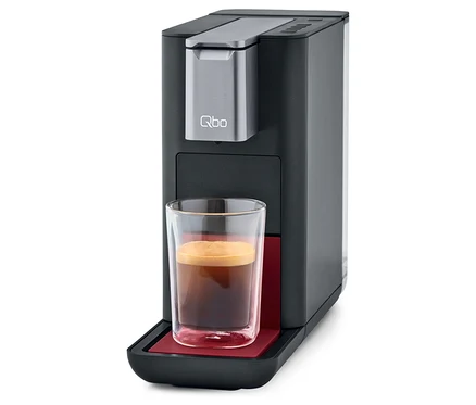 Qbo ESSENTIAL Dark Berry Kaffeemaschine mit Tasse Kaffee.