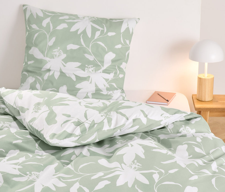Blumige Renforcé-Bettwäsche in Normalgröße auf einem Bett.