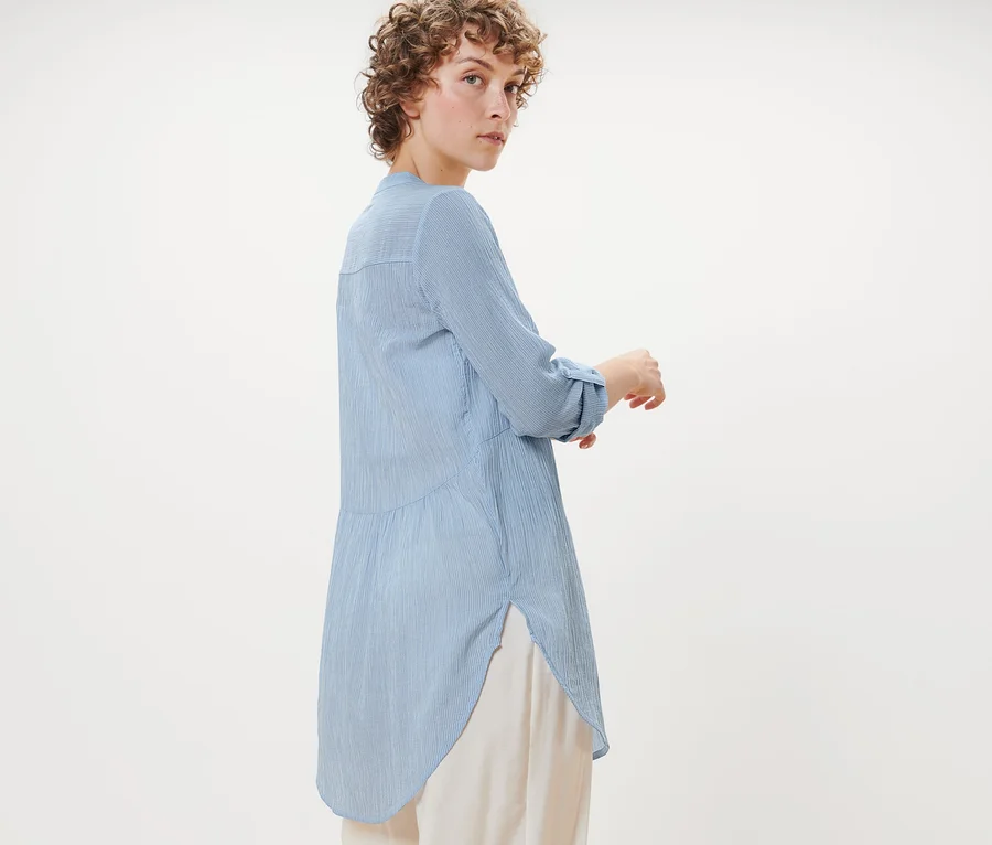 Frau posiert in gestreifter Longbluse.