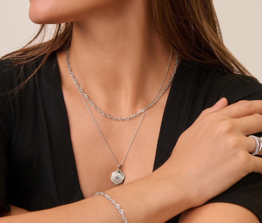 Frau trägt Silberschmuck: 925 Silber Ohrstecker Zirkoniabogen, 925 Silber Kette Singapur, 925 Silber Kette Hexagon, 925 Silber Ring Solitär, 925 Silber Armband Singapur und 925 Silber Ring Memory.