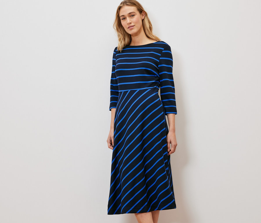 Frau steht und trägt ein gestreiftes Jerseykleid.