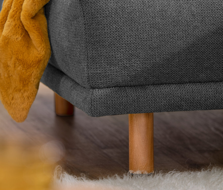 Detailansicht eines dunkelgrauen Ecksofas "Penelope" (links) mit einem gelben Tuch.