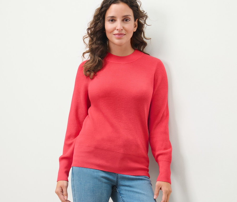 Frau posiert in einem Feinstrickpullover.
