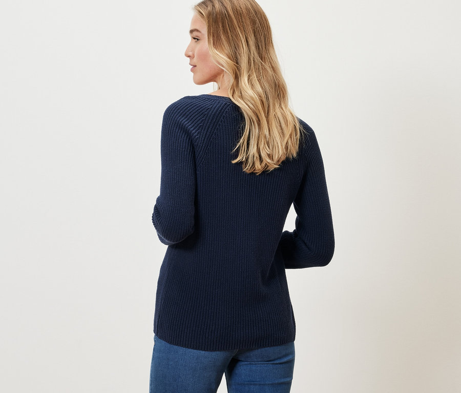 Blonde Frau trägt einen dunkelblauen Strickpullover.