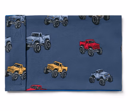 Stoff mit Monstertruck-Muster in Grau, Rot und Gelb auf blauem Hintergrund.