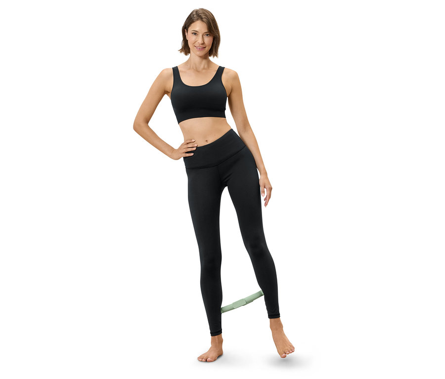 Frau trainiert mit einem Widerstandsband an den Beinen, bekleidet mit Sport-BH und Leggings.